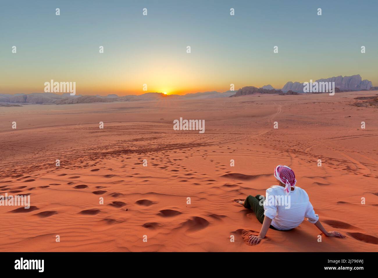 Woman enjoying the beautiful sunset in the Wadi Rum desert in Jordan, with views of the distant mountains. Stock Photo