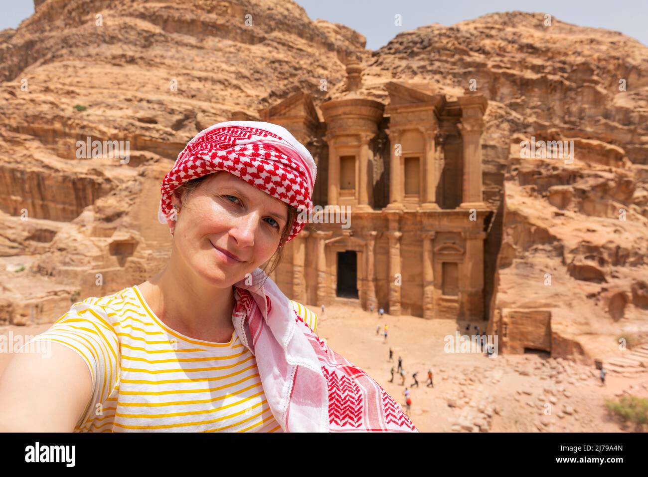 Beautiful young woman in colorful dress and kefiah enjoying at The Monastery, Petra's largest monument, UNESCO World Heritage Site, Jordan. Stock Photo