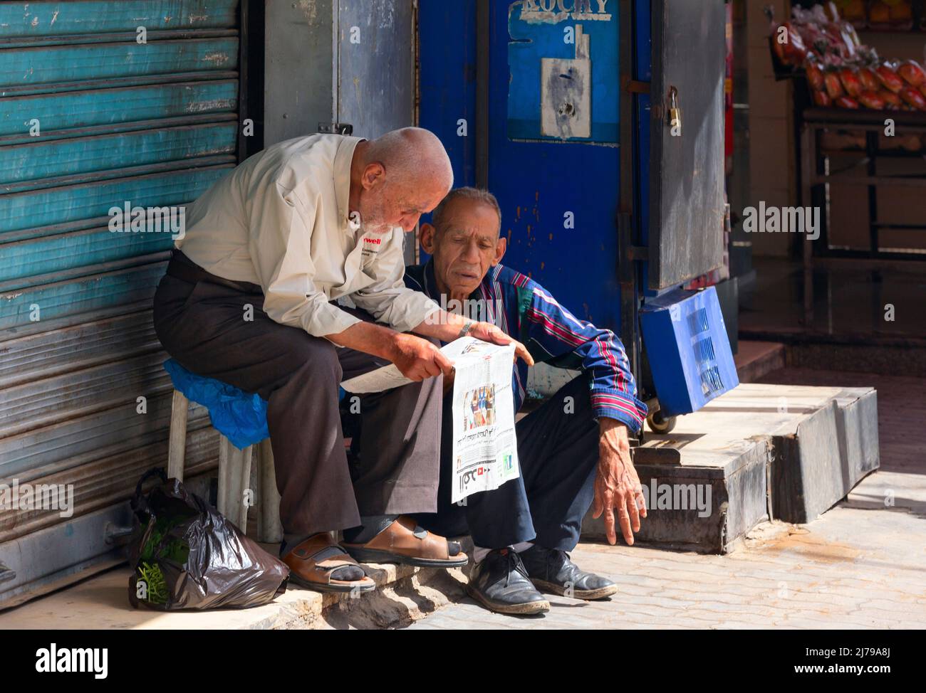 Jordan, Amman -  25-04-2022: two man reading newspaper at the side of the road. Stock Photo
