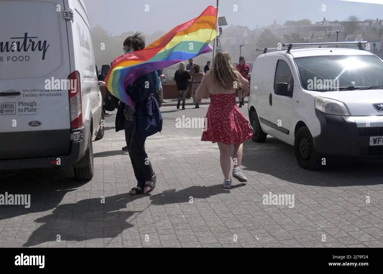 Falmouth Cornwall, UK 07th May 2022. A hero deputy town mayor replete with the chain of office and clutching her Rainbow pride flag is seen running towards a fire which has broken out in steak restaurant located in the Event square of Falmouth town. The Big Gay pride entertainment venue had to be evacuated for the safety of the crowds attending. Councillor Kirsty Edwards is a keen supporter of minority rights.  Falmouth Cornwall   Robert Taylor Alamy Live News Stock Photo