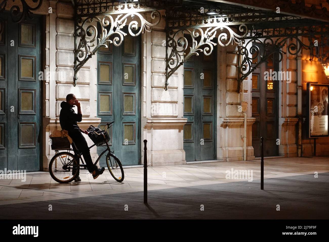 Nizza, ein Mann mit Mobiltelefon am Fahrrad vor der Oper // Nice, a man in front of the Opera House, sitting on a bicycle, using mobile phone Stock Photo