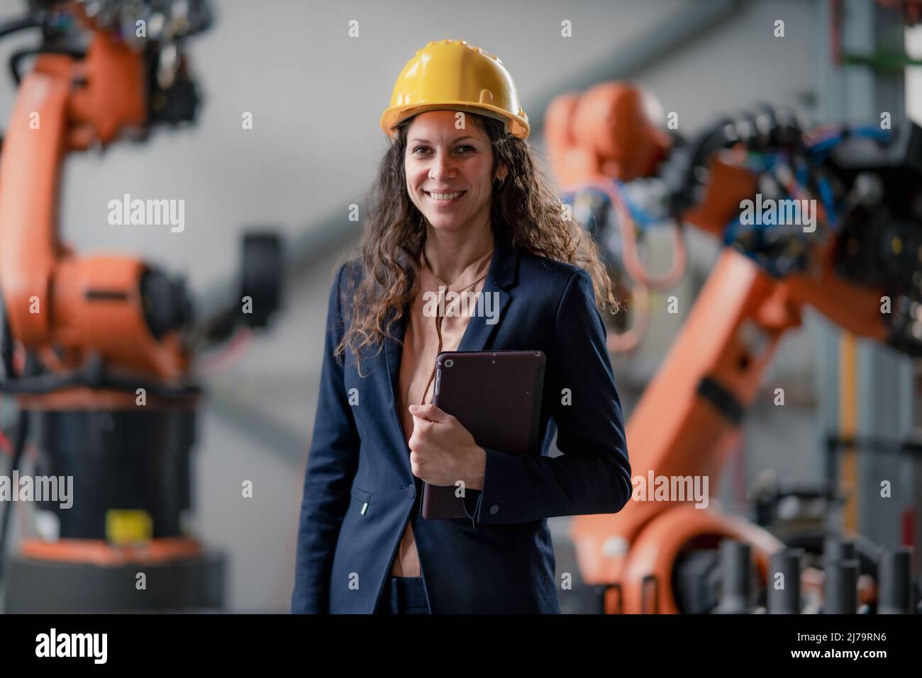 Automation female engineer with tablet for programming robotic arm in factory. Stock Photo