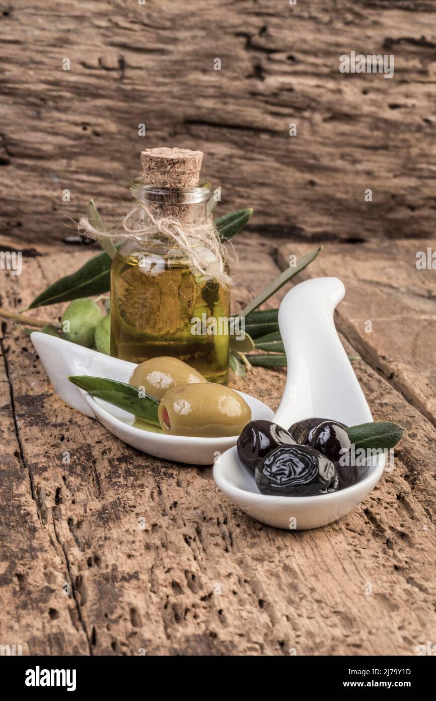Green and black olives and olive oil on wooden table Stock Photo - Alamy
