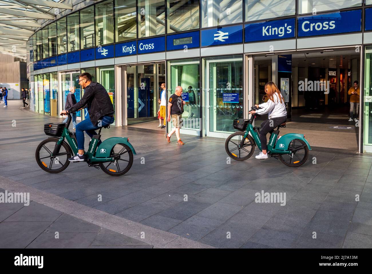 Kings Cross Station London - passengers ride hire bikes out of London Kings Cross Station. London Rental Bikes. Stock Photo