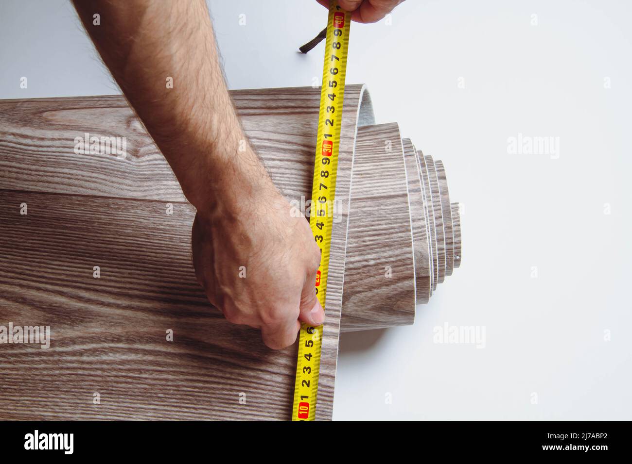 Measurement of linoleum on a cut. Man cuts linoleum. Tape measure and a man's hand with a piece