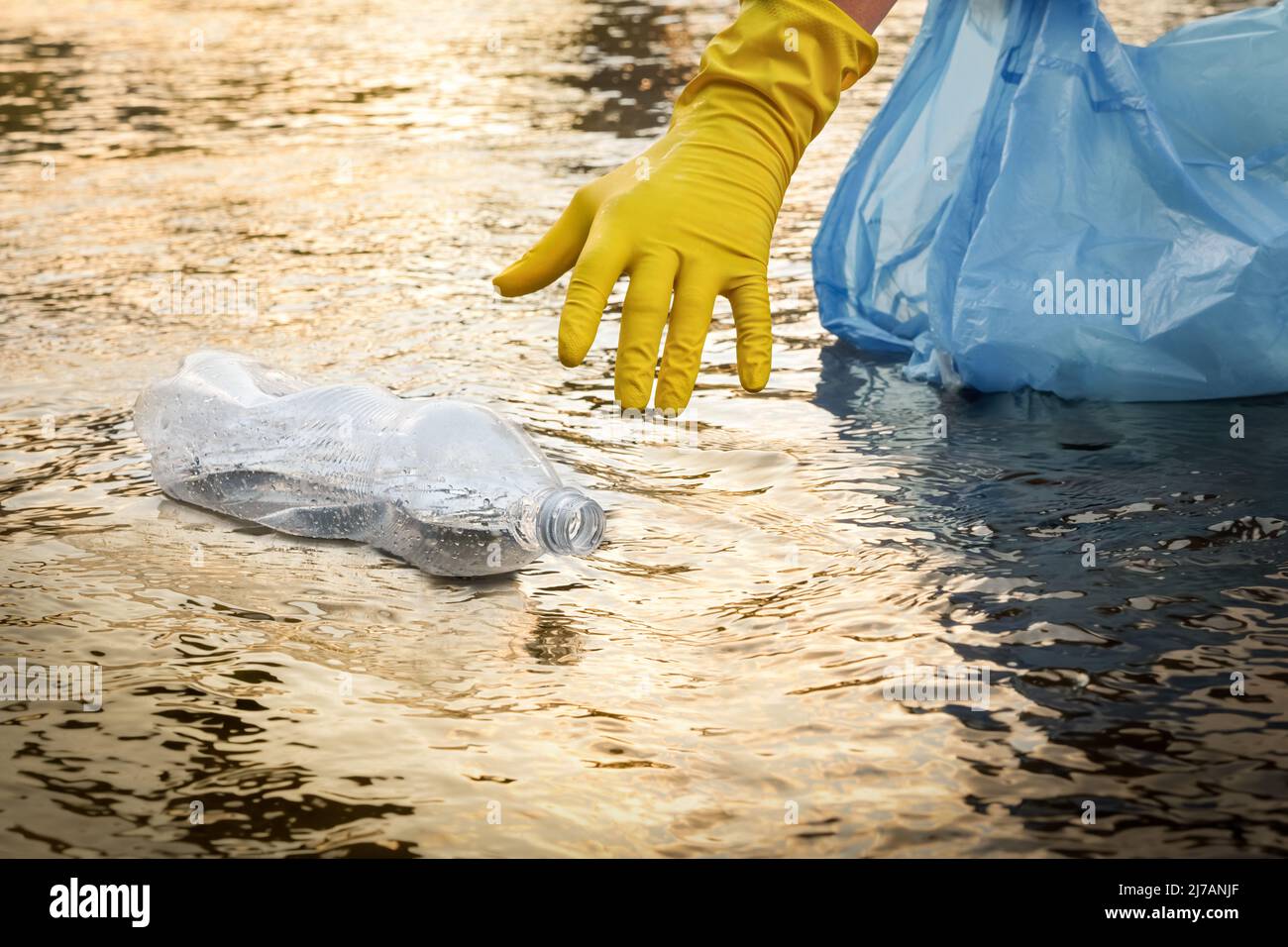 Collect garbage beach. Cleaning trash beach waste plastic PET bottle plastic pollution. Volunteer cleaning river trash pick up litter picking. Picking Stock Photo