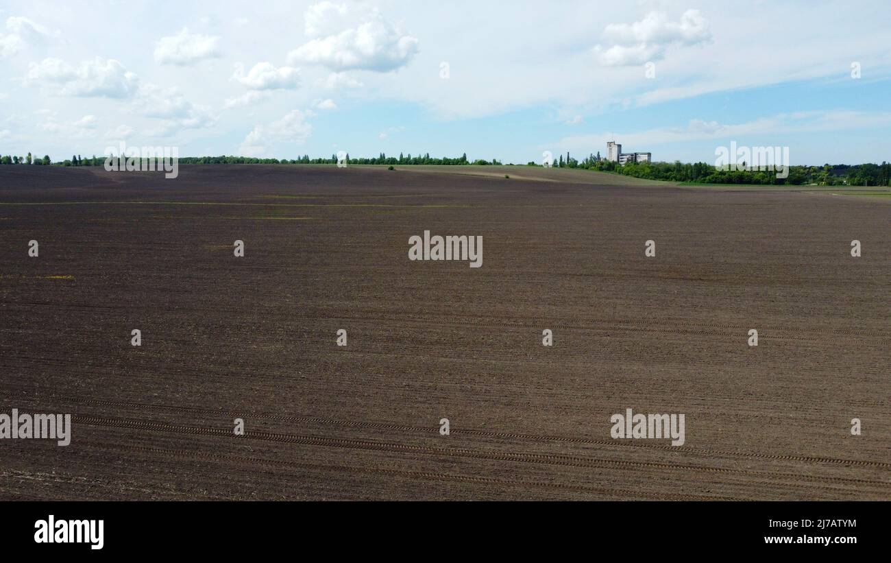 Aerial drone view flight over huge plowed field and blue sky. Skyline, horizon. Stock Photo