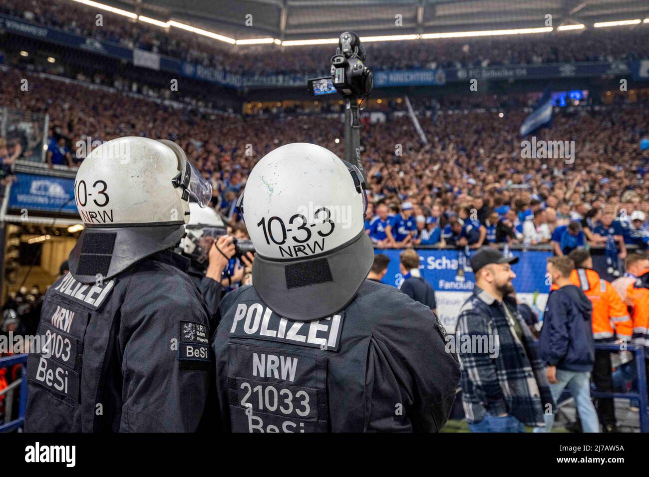 07 May 2022, North Rhine-Westphalia, Gelsenkirchen: Soccer: 2. Bundesliga, FC Schalke 04 - FC St. Pauli, 33rd matchday, Veltins Arena: Police officers film the fans storming the pitch. Photo: David Inderlied/dpa - IMPORTANT NOTE: In accordance with the requirements of the DFL Deutsche Fußball Liga and the DFB Deutscher Fußball-Bund, it is prohibited to use or have used photographs taken in the stadium and/or of the match in the form of sequence pictures and/or video-like photo series. Stock Photo