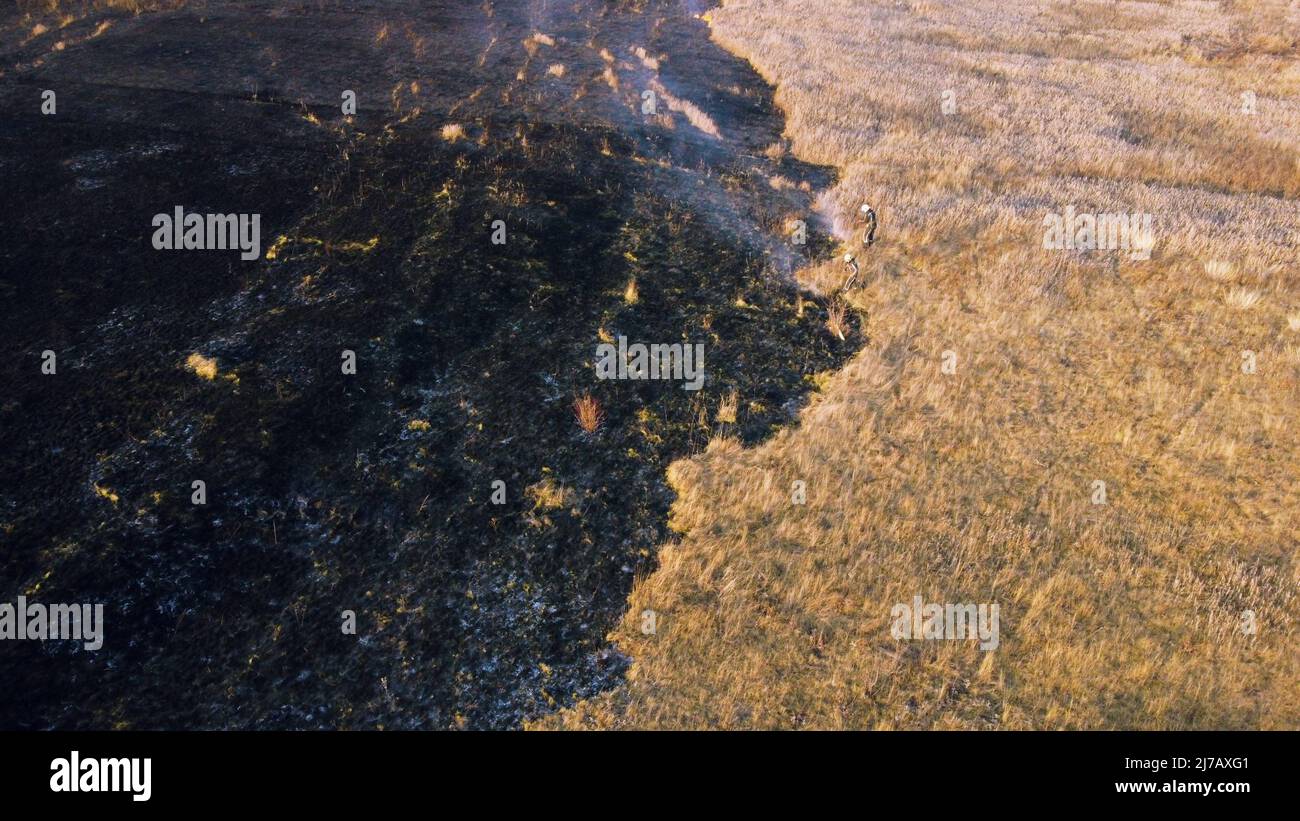 Aerial Drone View two firefighters putting out fire in field with dry grass Stock Photo Alamy