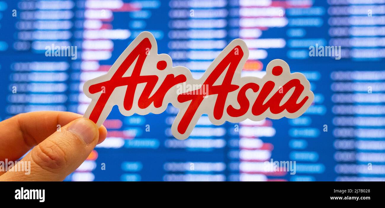 December 11, 2021, Kuala Lumpur, Malaysia. The emblem of AirAsia airline against the background of an electronic scoreboard with flight schedules at t Stock Photo