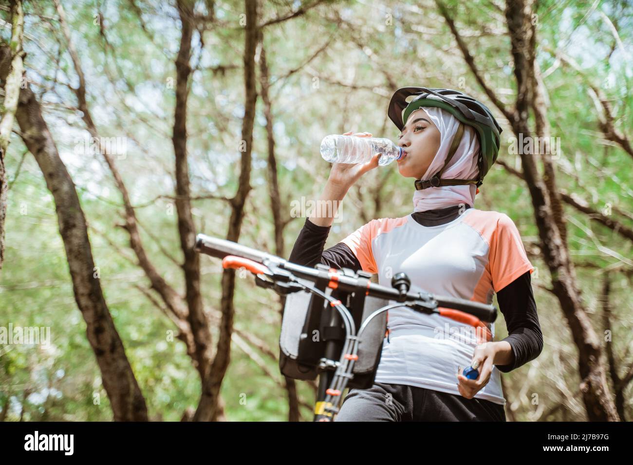 Woman in hijab drinking mineral water bottle when thirsty Stock Photo ...