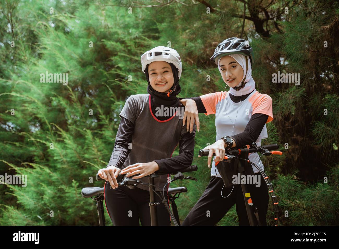 two women in veil happy while cycling together Stock Photo Alamy