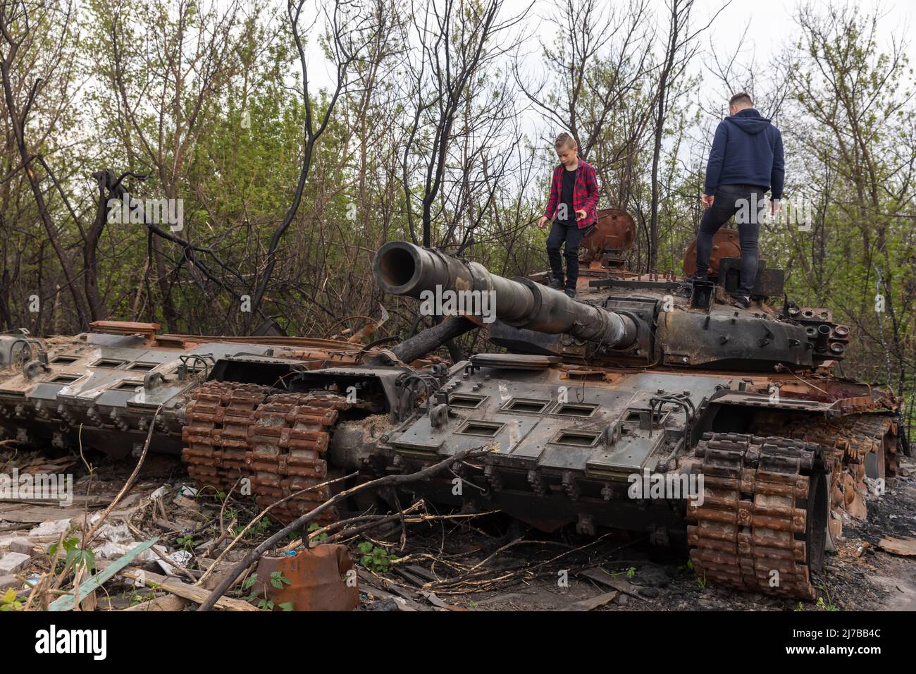 A youth and a boy stand on the tower of a destroyed Russian tank near Makariv village, Kyiv region. Russia invaded Ukraine on 24 February 2022, triggering the largest military attack in Europe since World War II. Stock Photo