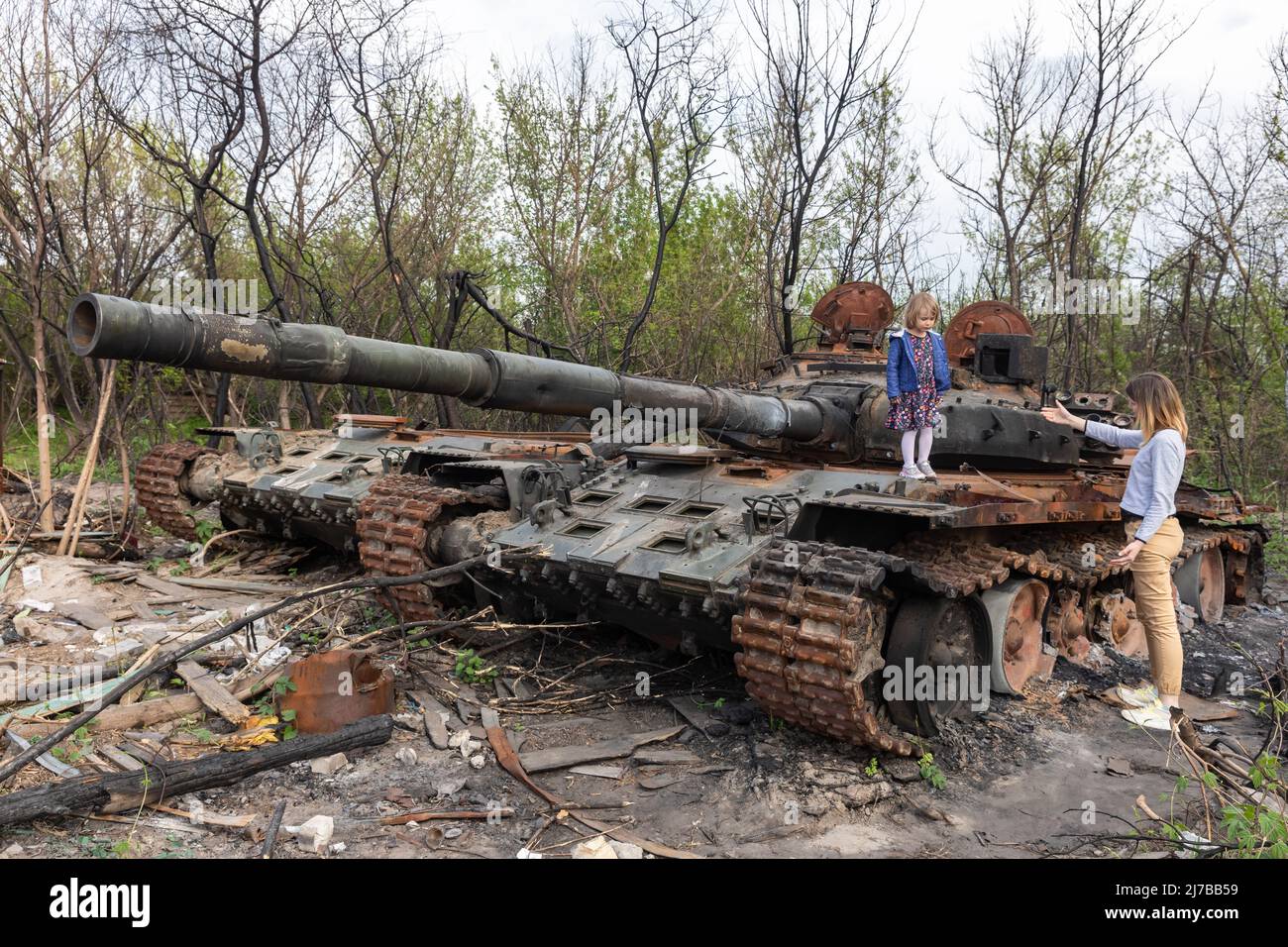 A girl stands on the tower of a destroyed Russian tank near Makariv village, Kyiv region. Russia invaded Ukraine on 24 February 2022, triggering the largest military attack in Europe since World War II. Stock Photo