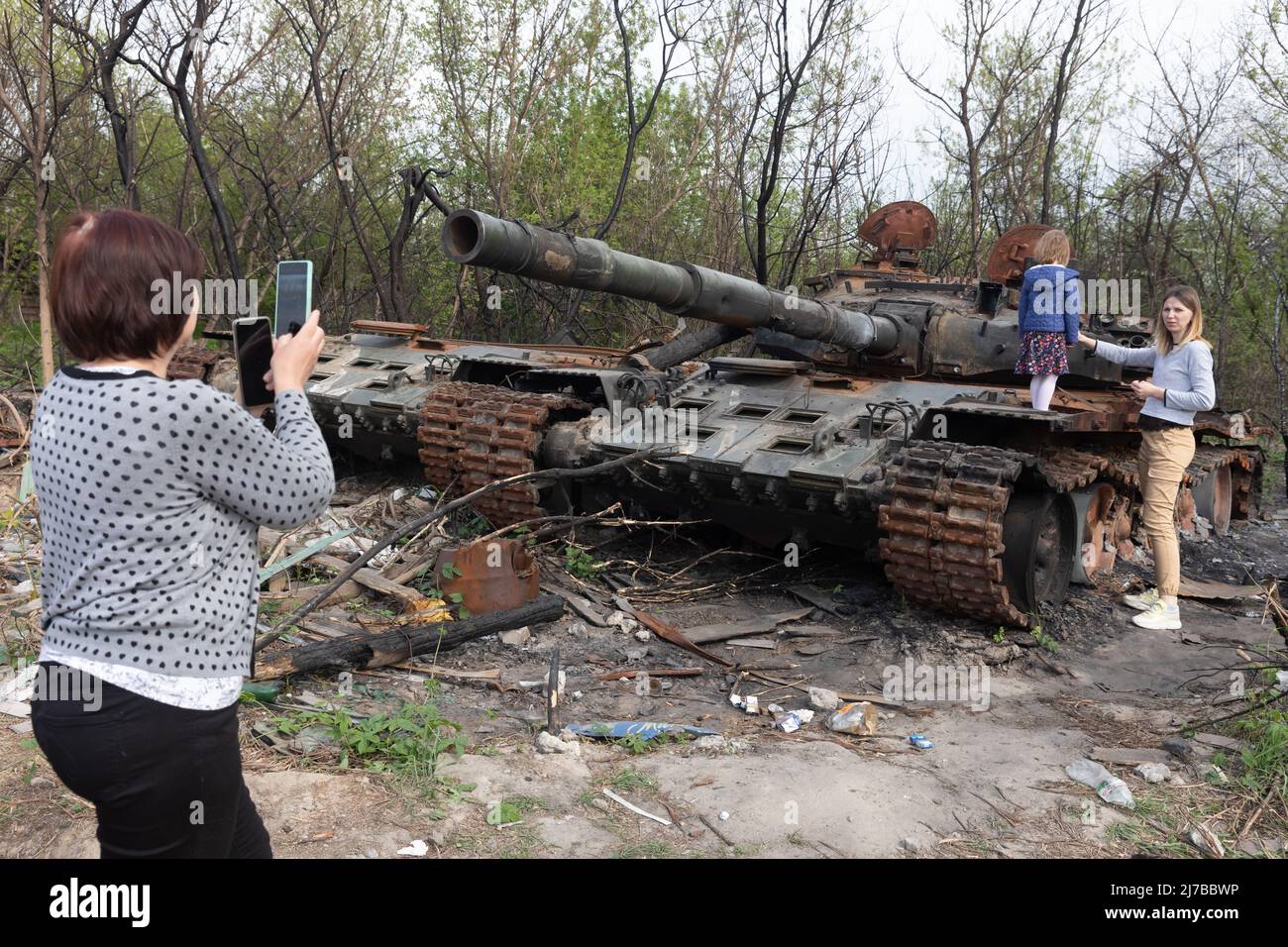 A woman takes photos of a girl standing on the tower of a destroyed Russian tank near Makariv village, Kyiv region. Russia invaded Ukraine on 24 February 2022, triggering the largest military attack in Europe since World War II. (Photo by Mykhaylo Palinchak / SOPA Images/Sipa USA) Stock Photo