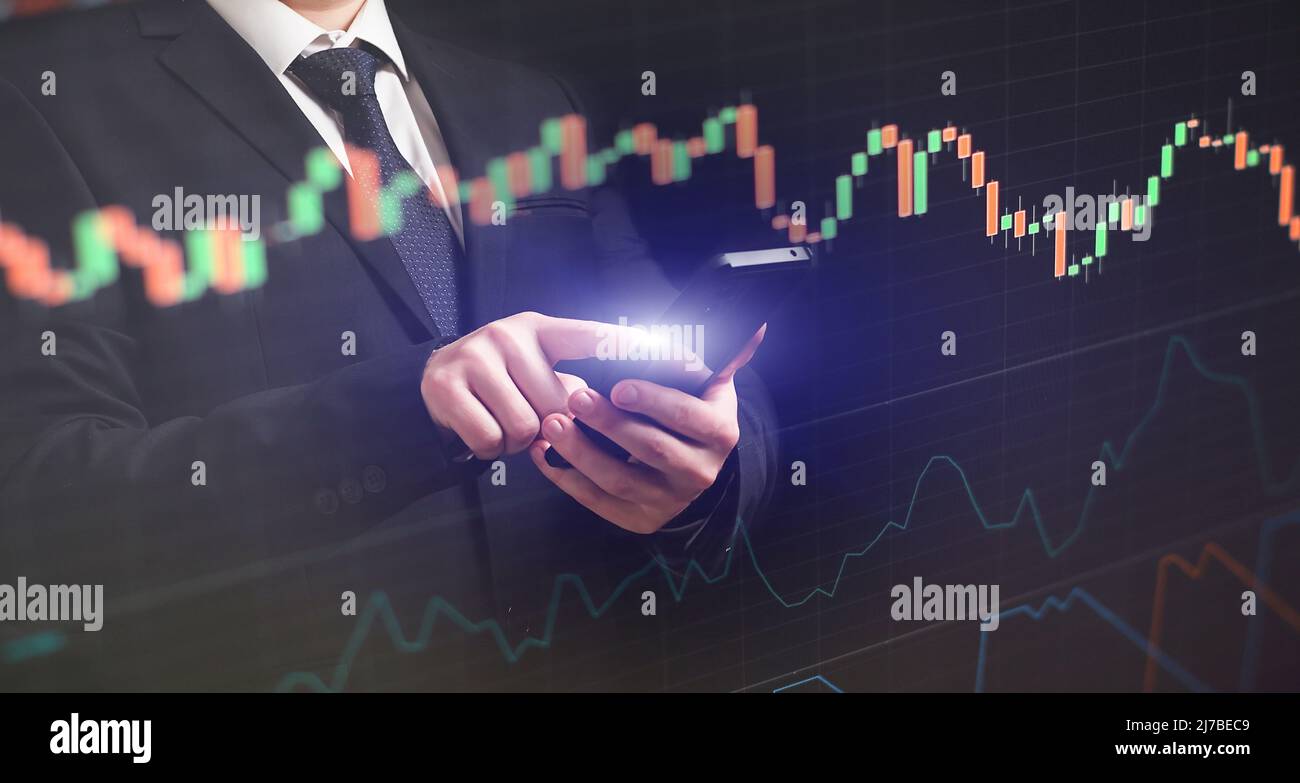 Man using smartphone with graphs analysis candle line and foreign currency rate on bokeh colors light. Manager analyzing investment statistics and ind Stock Photo
