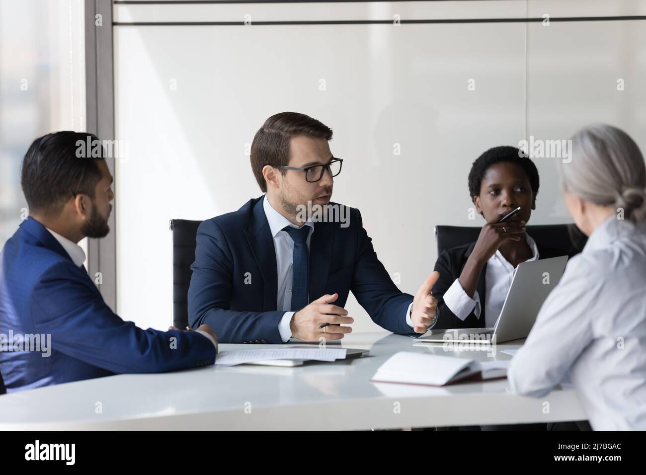 Diverse group of serious business partners negotiating on deal Stock Photo