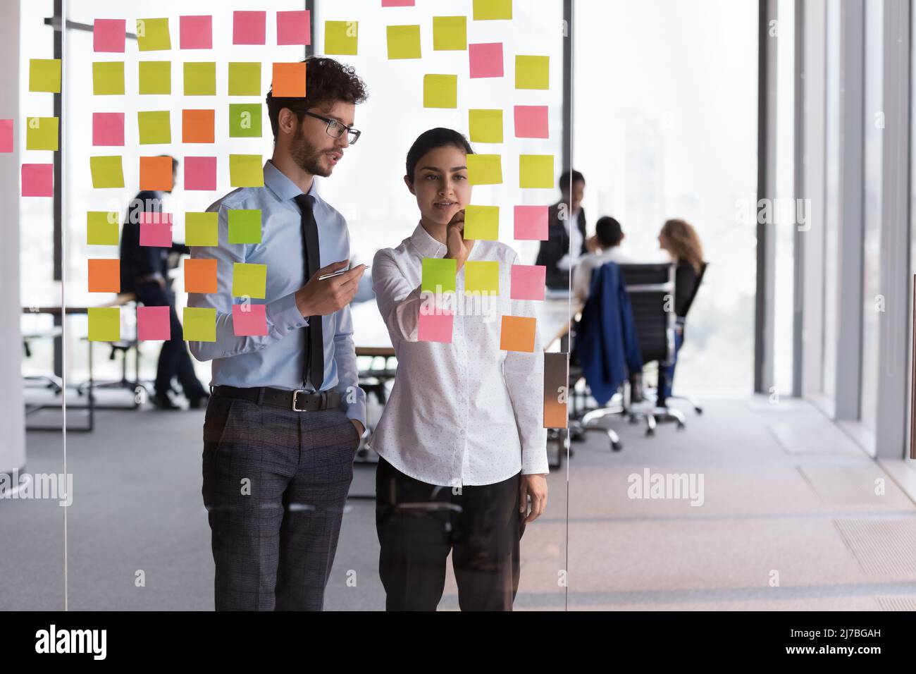 Confident Indian mentor woman teaching young Intern guy Stock Photo