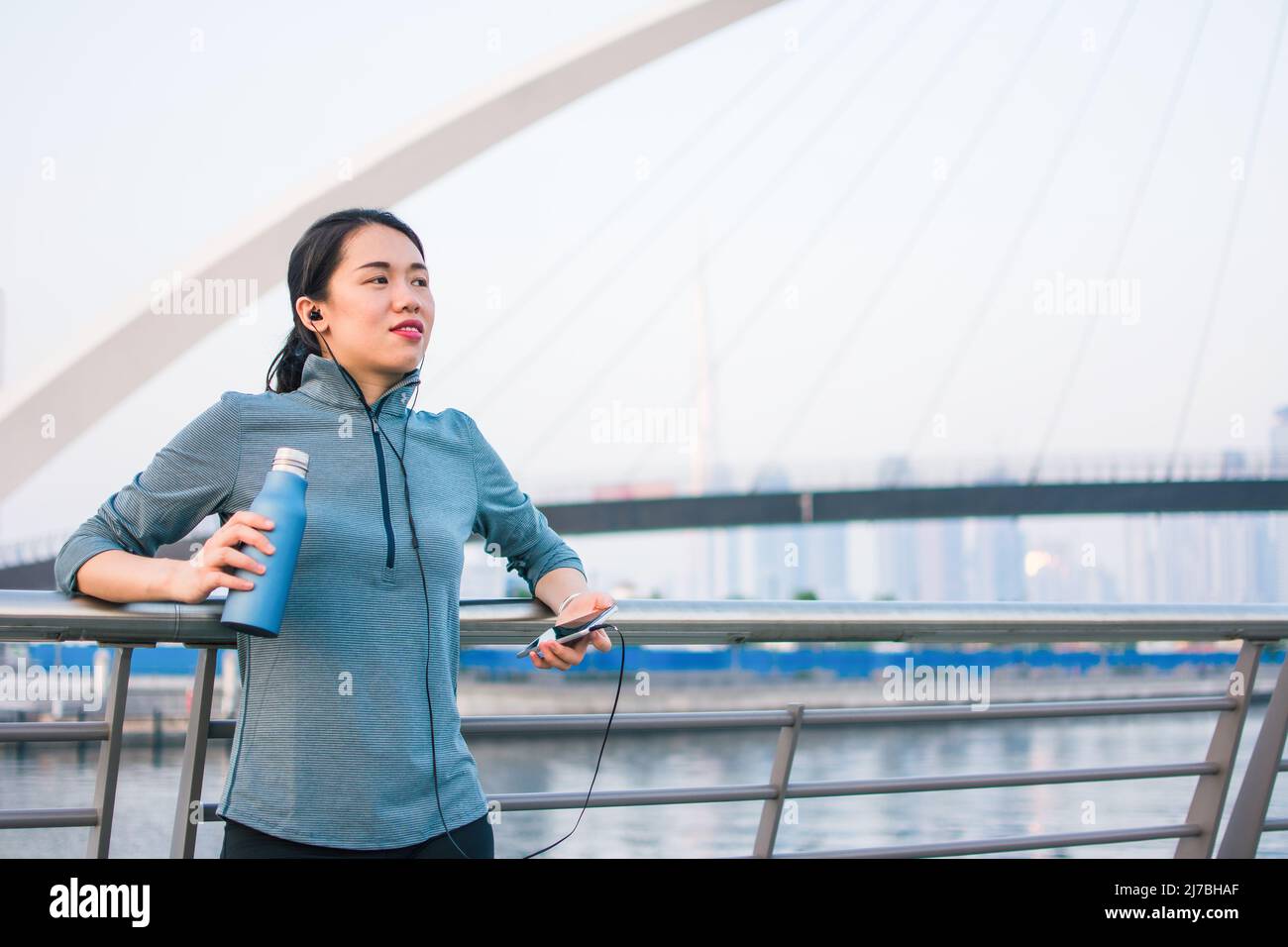 Fit Asian woman taking rest from an outdoors workout and running outdoors in Dubai Stock Photo