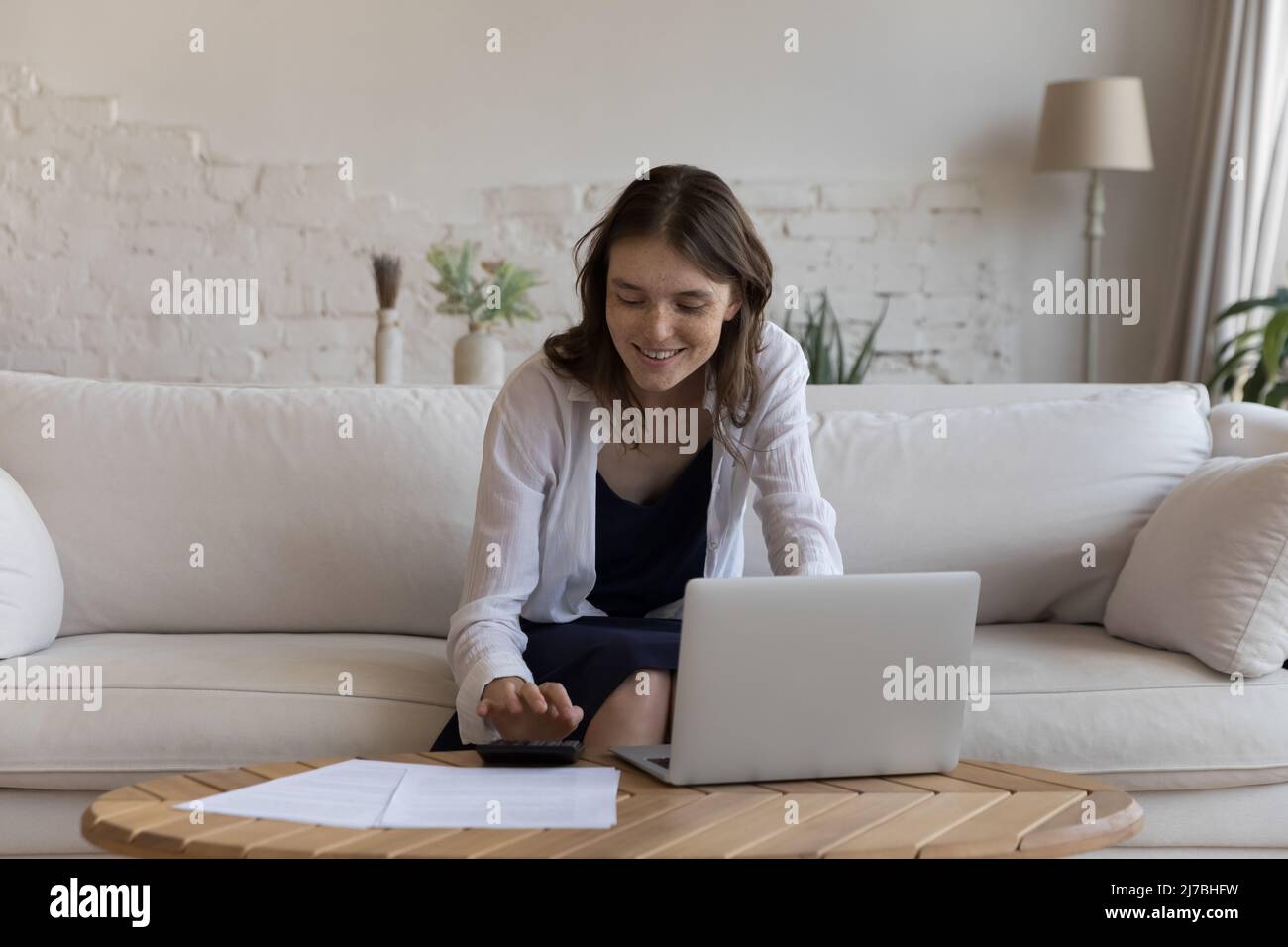 Positive satisfied young tenant woman doing accounting work Stock Photo