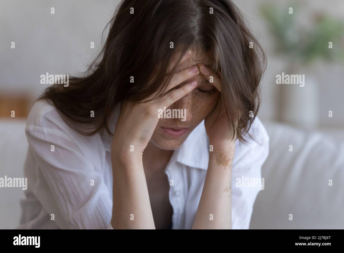 Tired frustrated millennial girl touching head, feeling headache Stock Photo