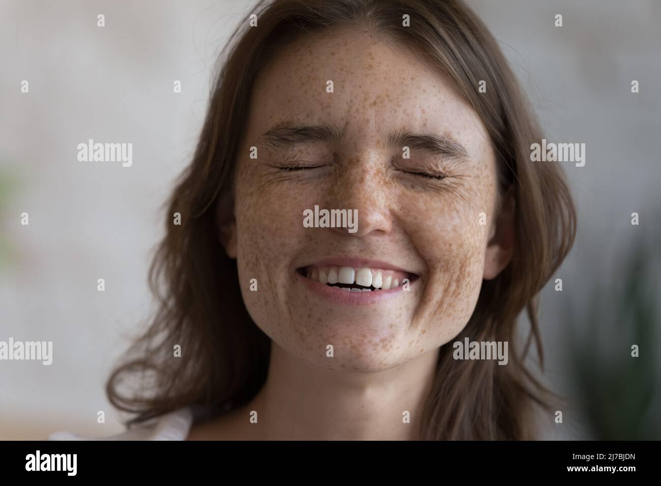 Cheerful excited freckled teen girl laughing with closed eyes Stock Photo