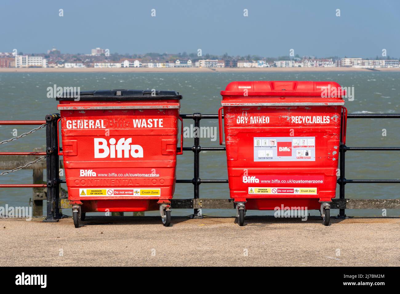 Two red waste bins on Southend Pier, Southend on Sea, Essex, UK. Out in the Thames Estuary. Distant waste collection. General waste and recyclables Stock Photo