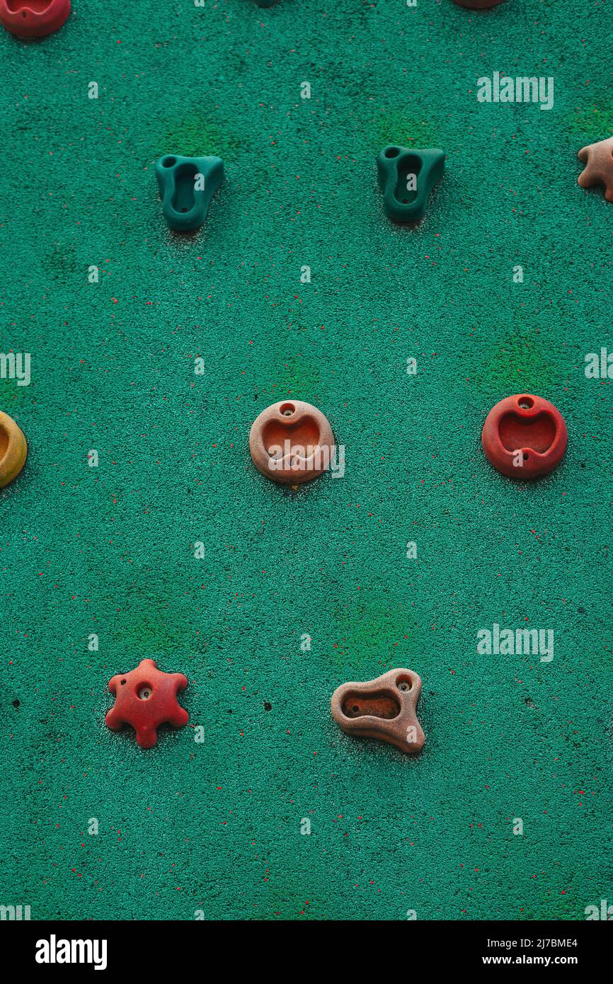 childish climbing holds on green tartan, located on a kids playground for learning how to climb Stock Photo