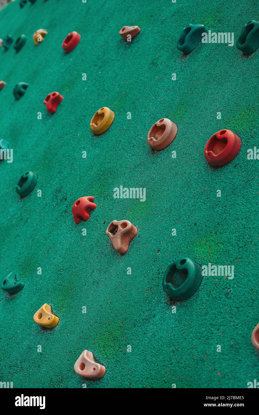 childish climbing holds on green tartan, located on a kids playground for learning how to climb Stock Photo
