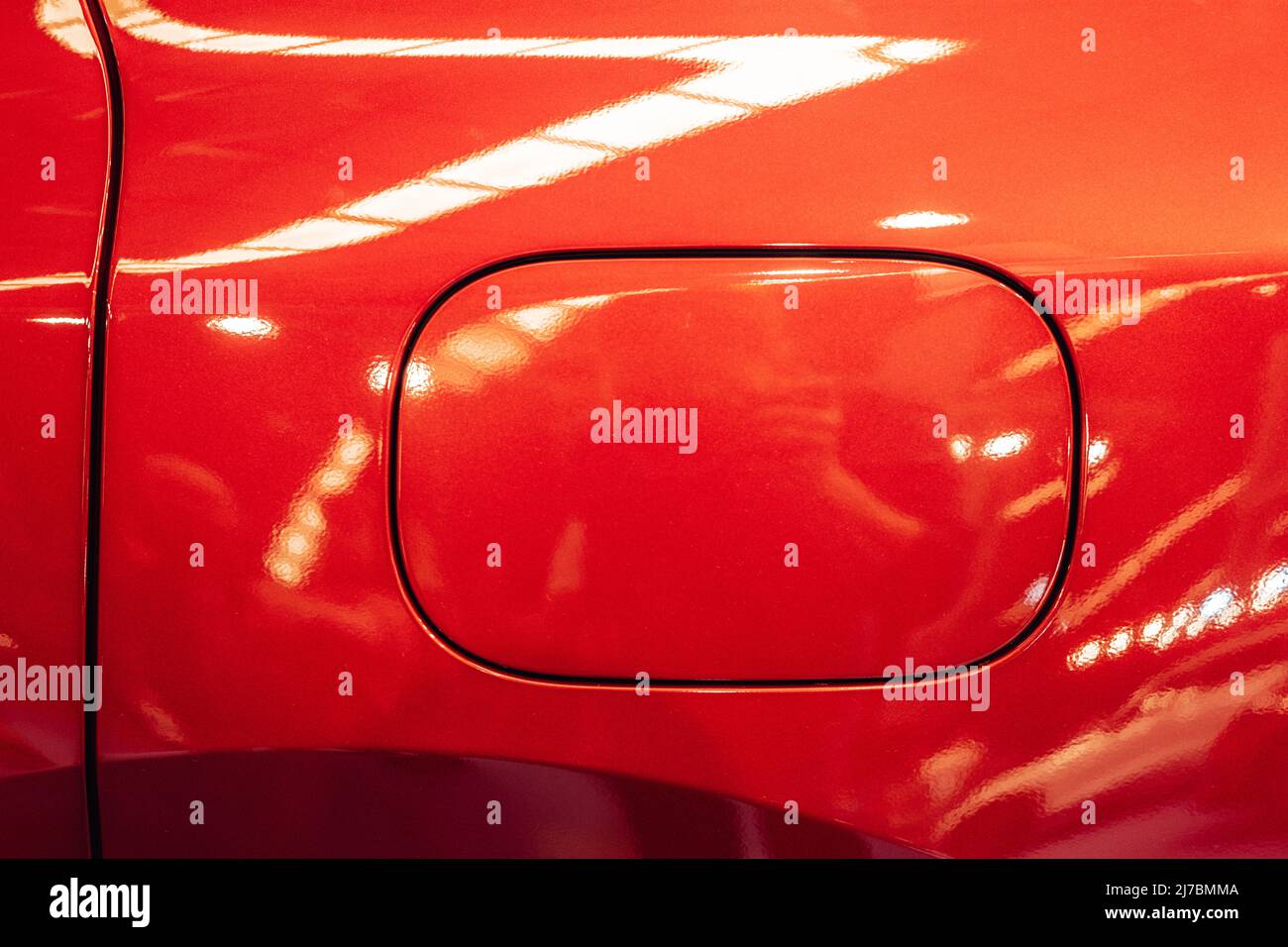 Detail of the fuel tank entry on a red car with metallic reflections