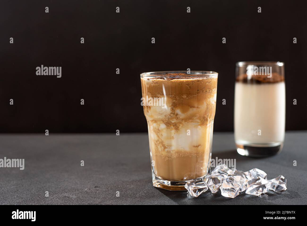 Dalgona coffee with ice on dark background. Horizontal view, copy space. Stock Photo