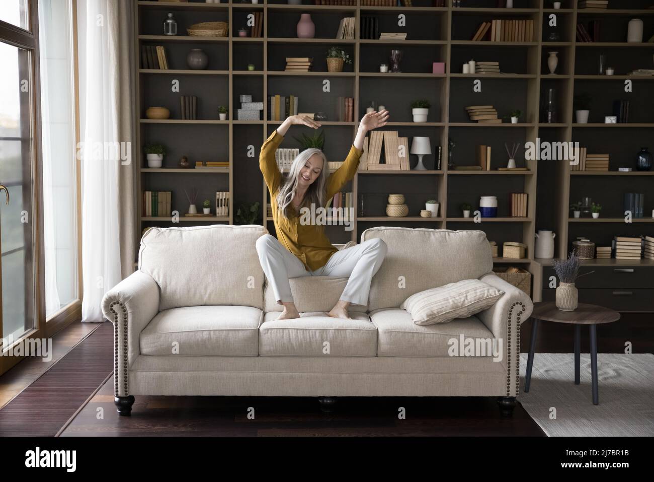 Happy cheerful mature woman dancing on home sofa Stock Photo - Alamy
