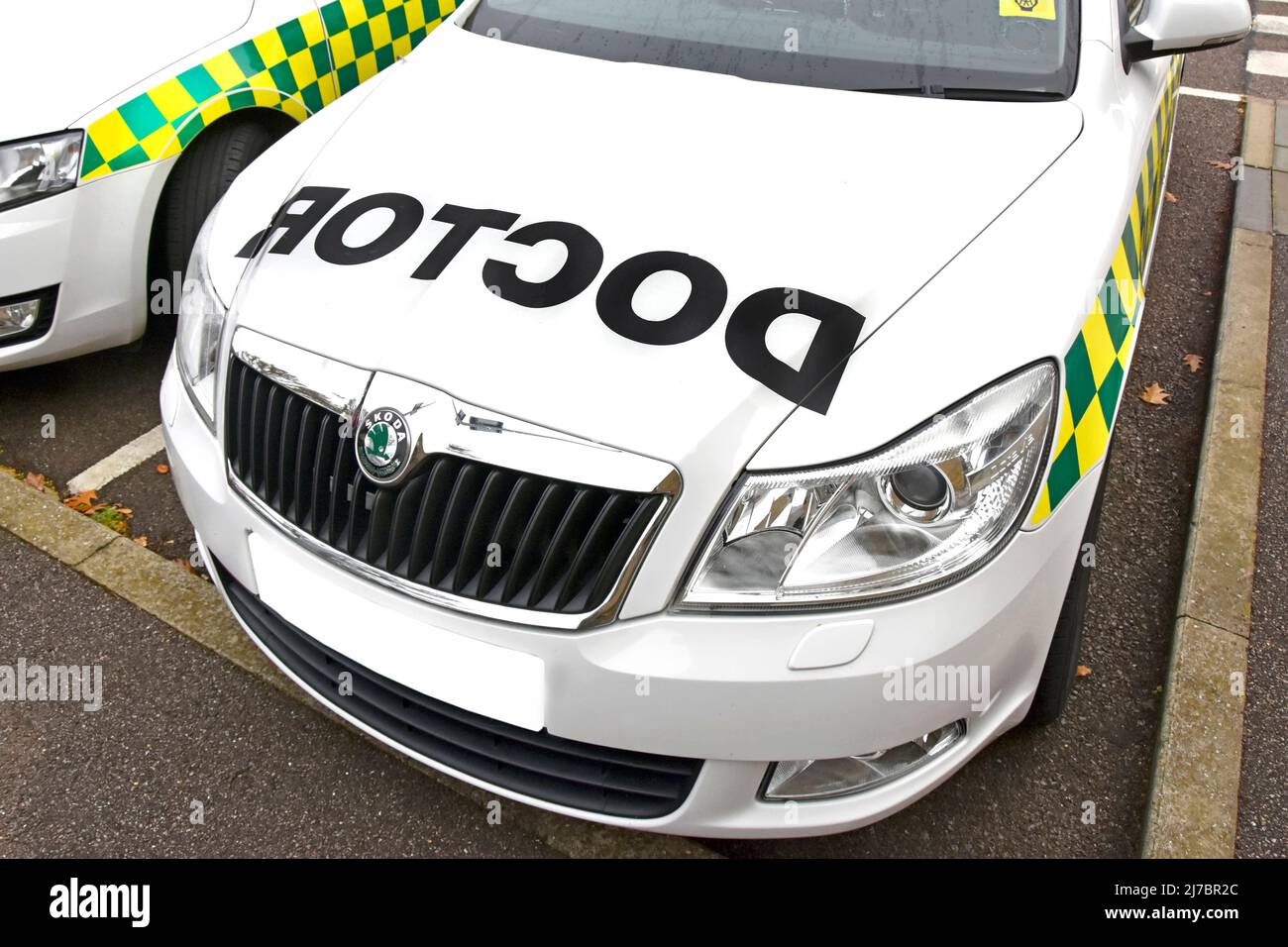 Front view white Skoda NHS doctors car emergency healthcare transport vehicle reverse text letters image on bonnet obscured number plate England UK Stock Photo