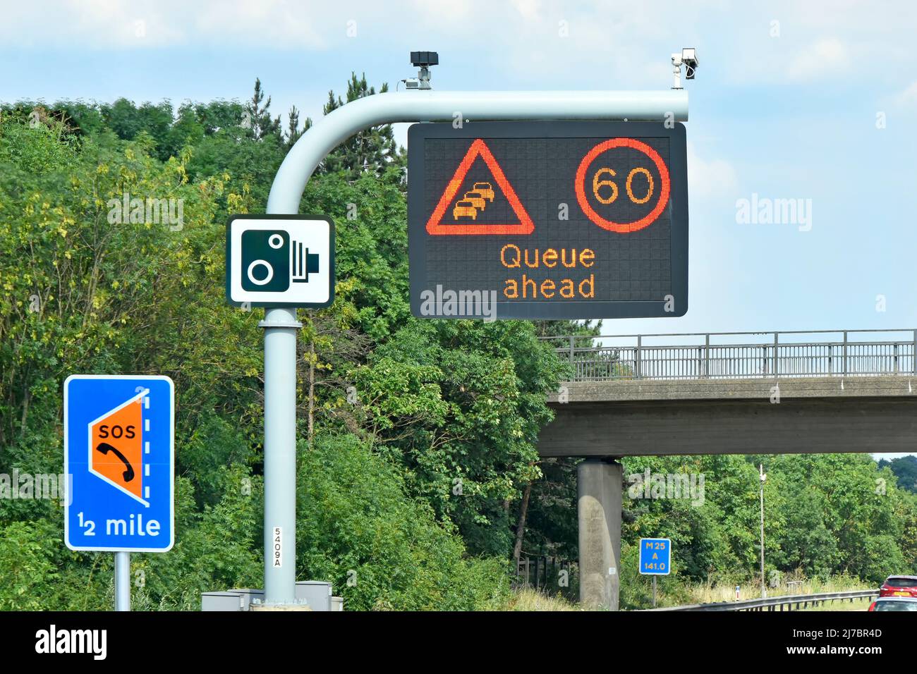 Single panel M25 motorway sign above lane one 60MPH variable speed limit & Queue Ahead message & smart lane layby half mile & standard camera signs UK Stock Photo