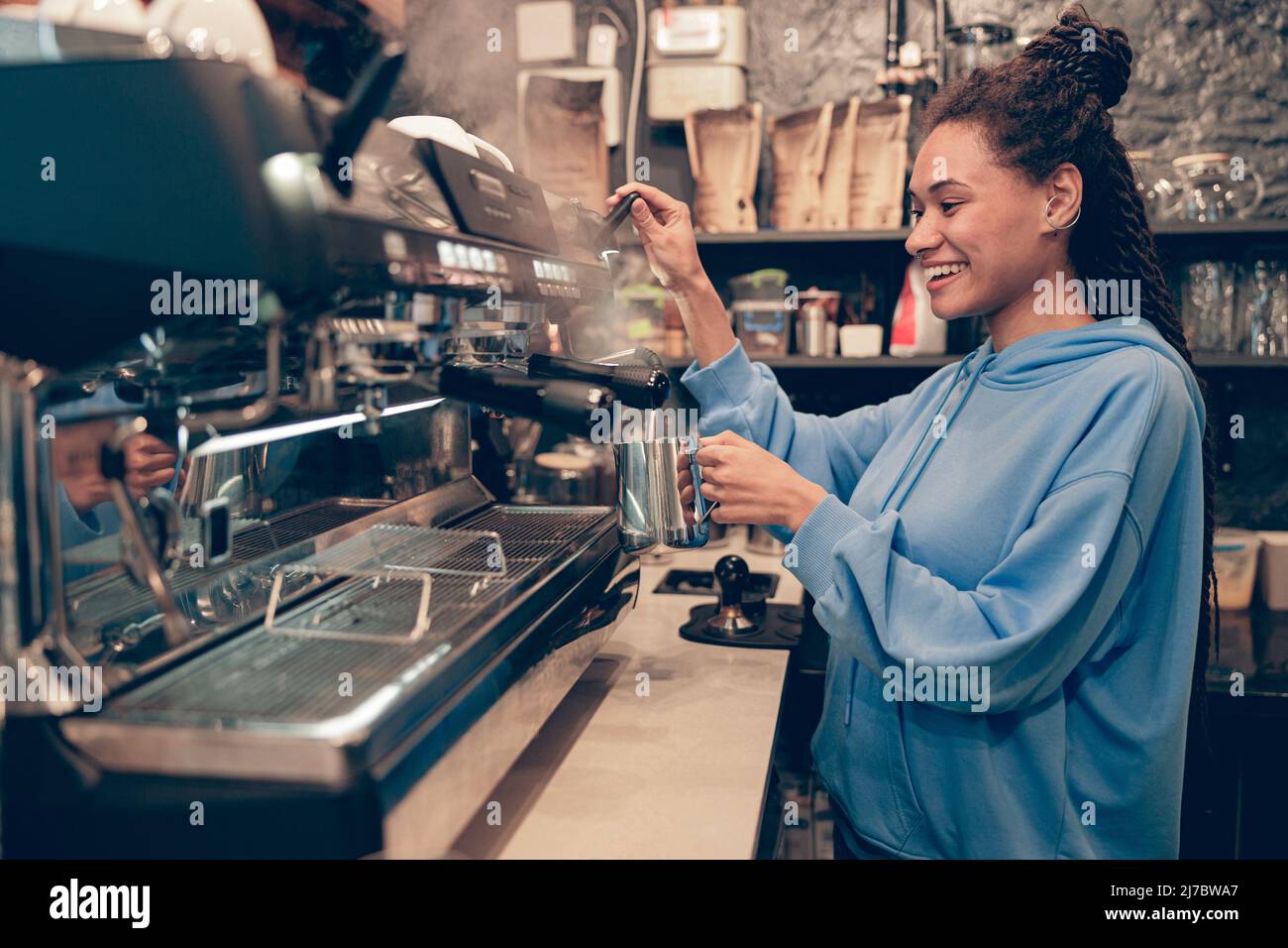 Stylish happy female bartender making coffee at professional machine. Work in cafeteria. Stock Photo