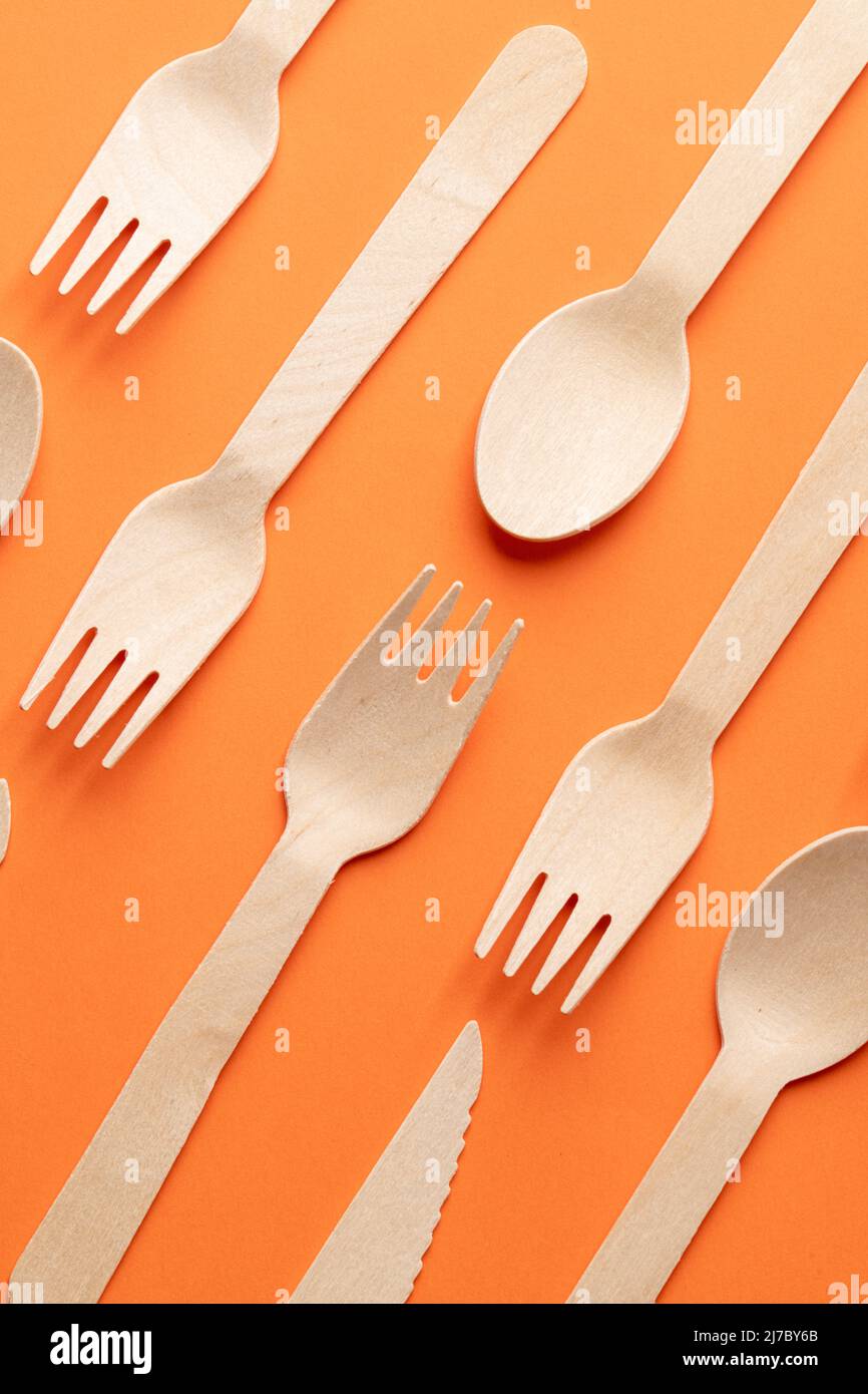 Disposable wooden cutlery on a orange background. Environmentally