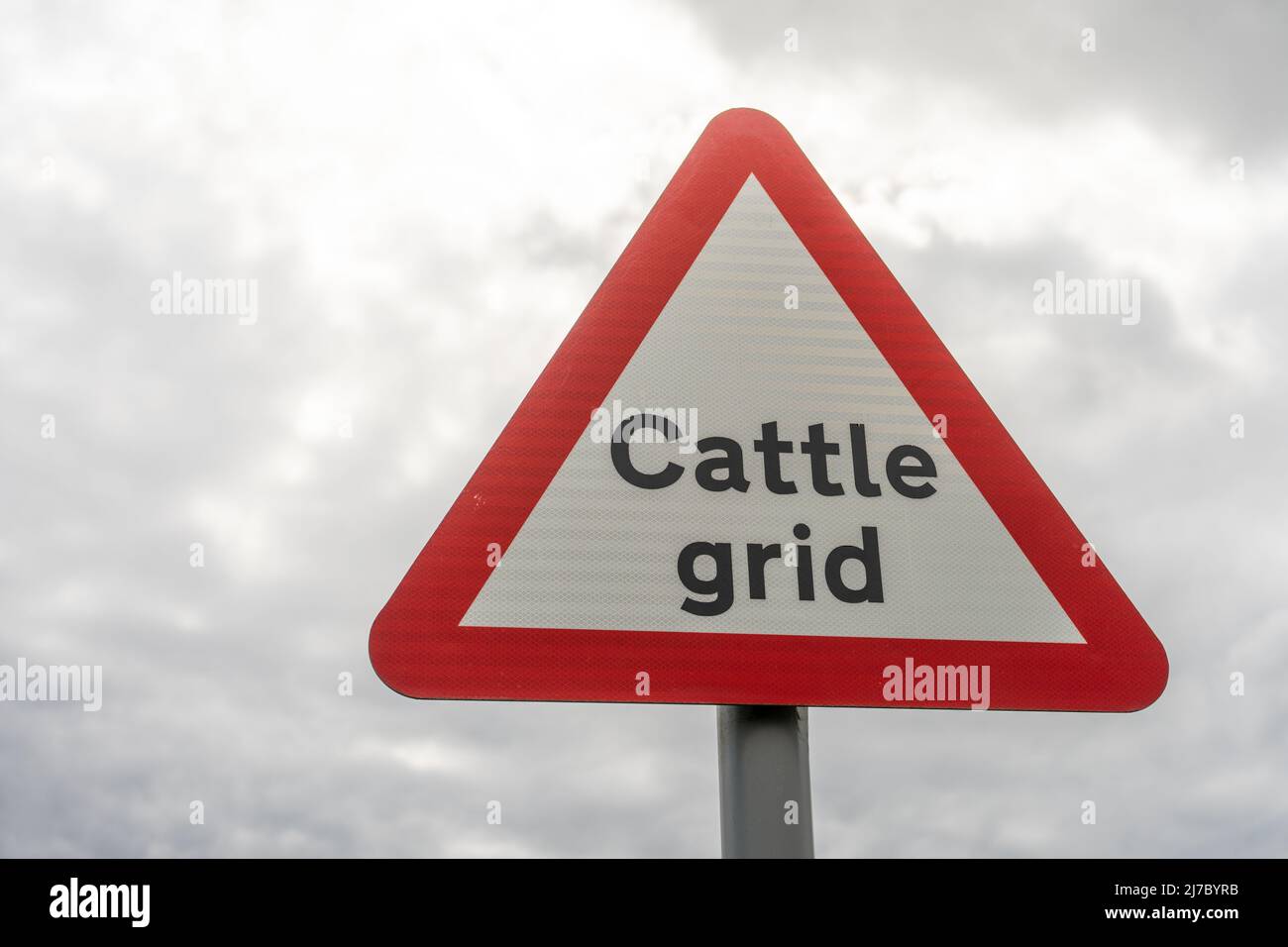 A sign for a cattle grid - an indicator of the countryside, against a sunny clouded sky, Near Walltown, Northumberland, UK Stock Photo