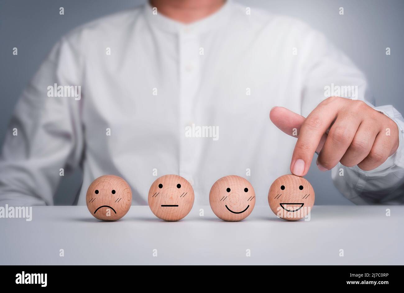 Customer service evaluation, feedback, client experience, and satisfaction survey concepts. Happy face emoticon wooden ball was chosen by the customer Stock Photo
