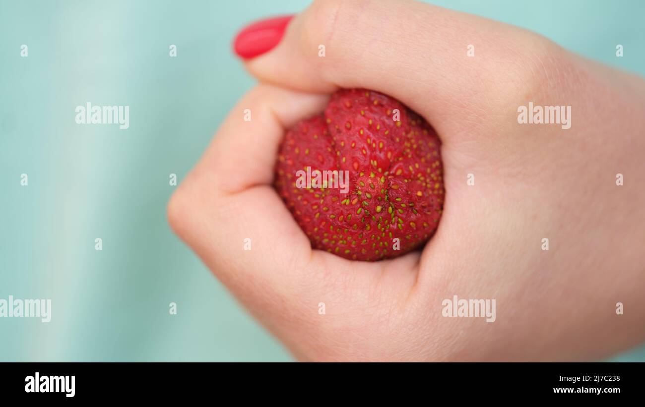 Problematic colon anatomy in hands. Clenched strawberry ina fist concept Stock Photo