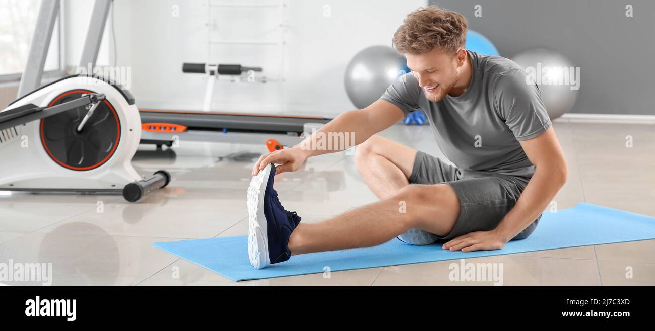 Sporty young man stretching in gym Stock Photo - Alamy