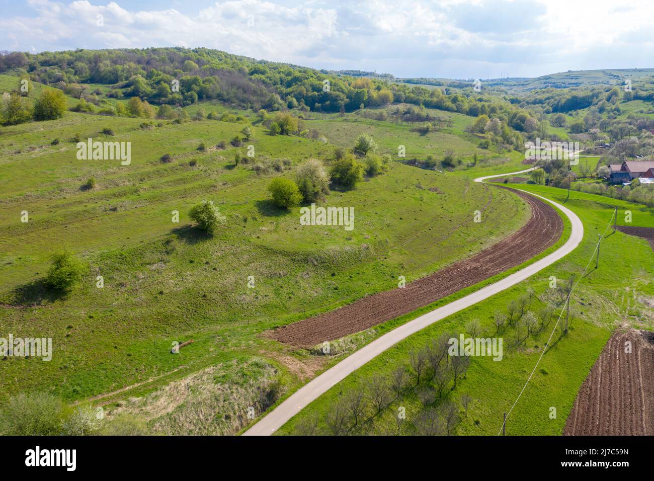 Aerial view of village road passing near an agricultural field. Spring ...