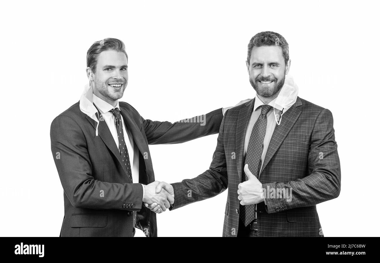 colleagues in respirator mask shaking hands after successful deal during pandemic, business meeting. Stock Photo
