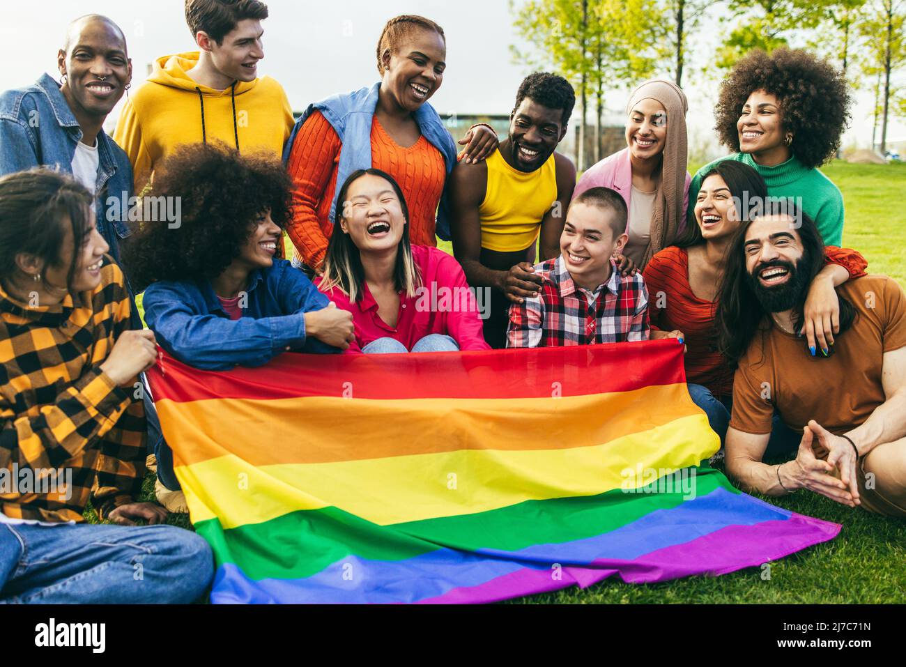 Diverse people having fun holding LGBT rainbow flag outdoor - Focus on center african woman face Stock Photo