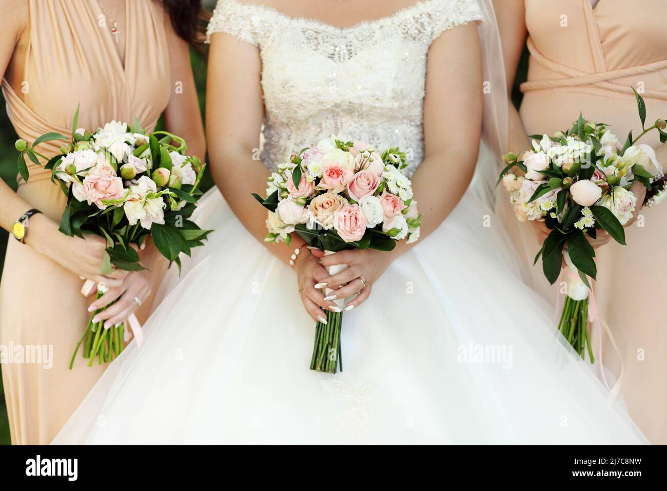 Bride and bridesmaids holding with wedding bouquets on their hands ...