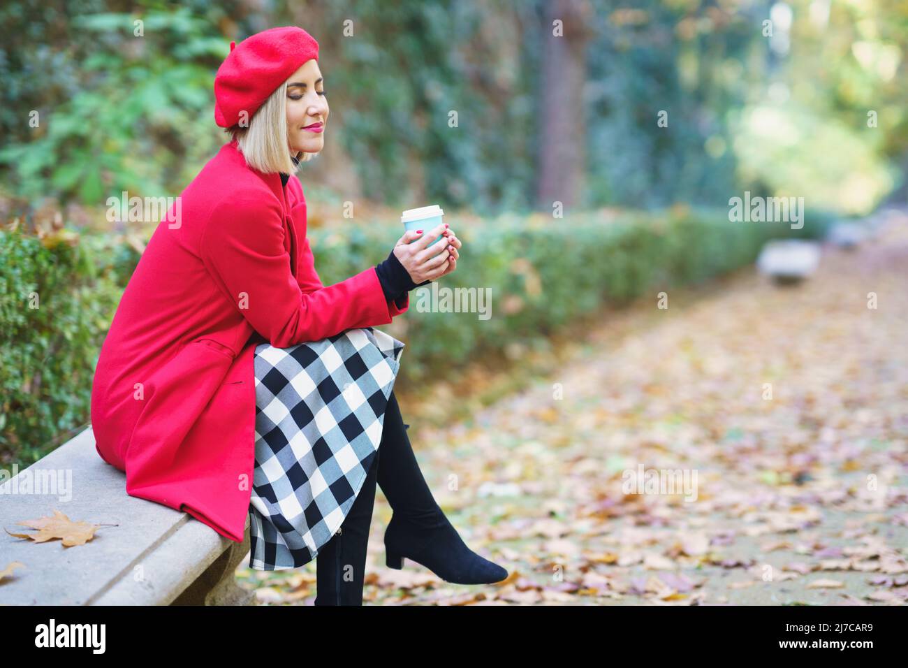 Stylish woman with takeaway beverage in autumnal park Stock Photo