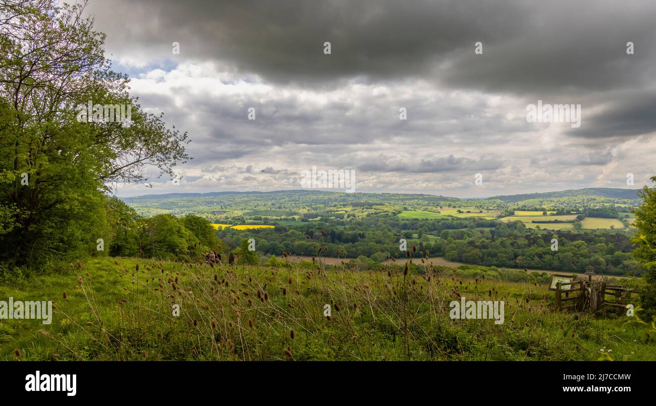 View of countryside at Blatchford Down, Abinger Hammer in the Surrey Hills Area of outstanding Natural Beauty, sun in the valley, dark stormy clouds Stock Photo