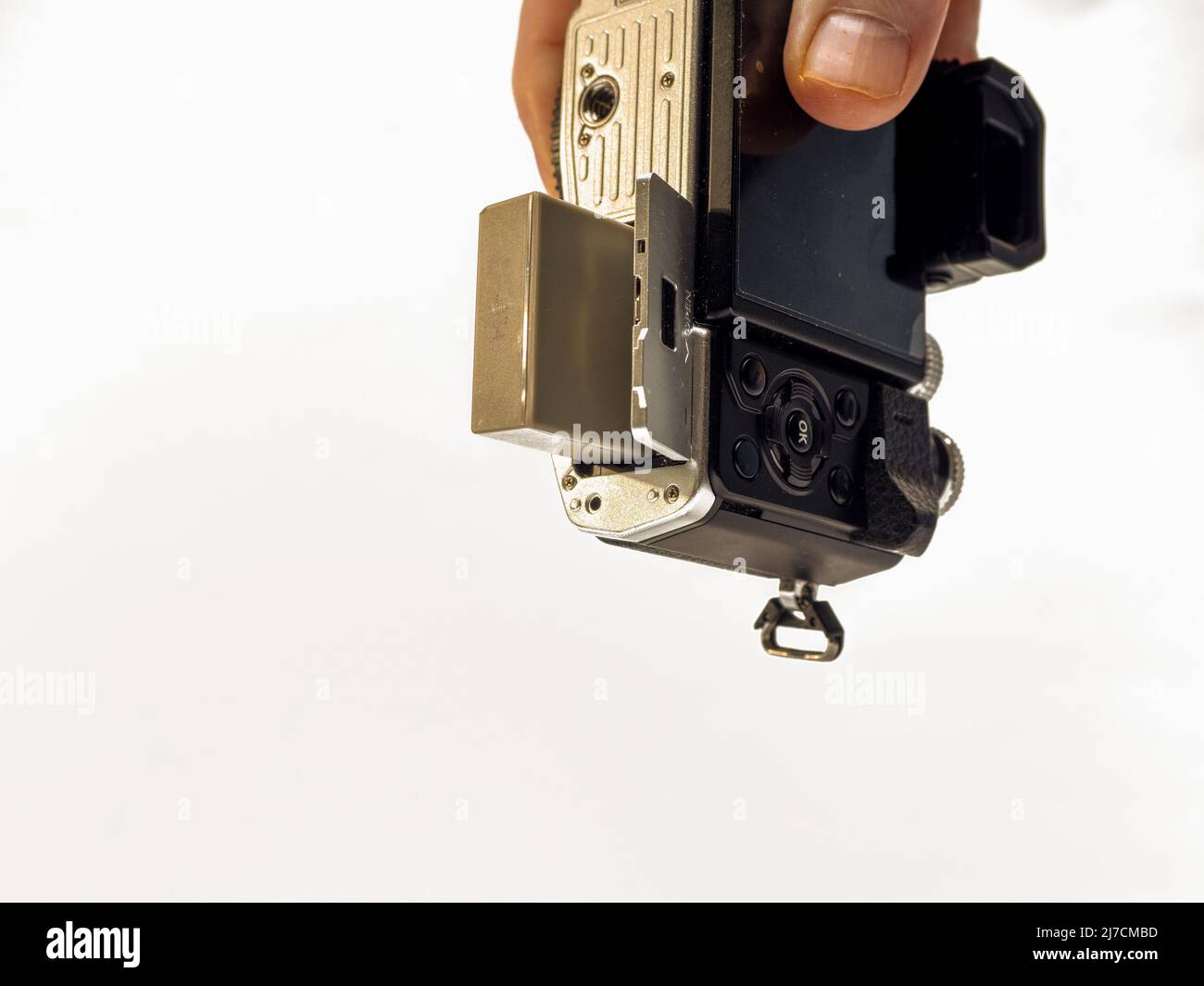 holding a mirrorless camera with battery door compartment open to