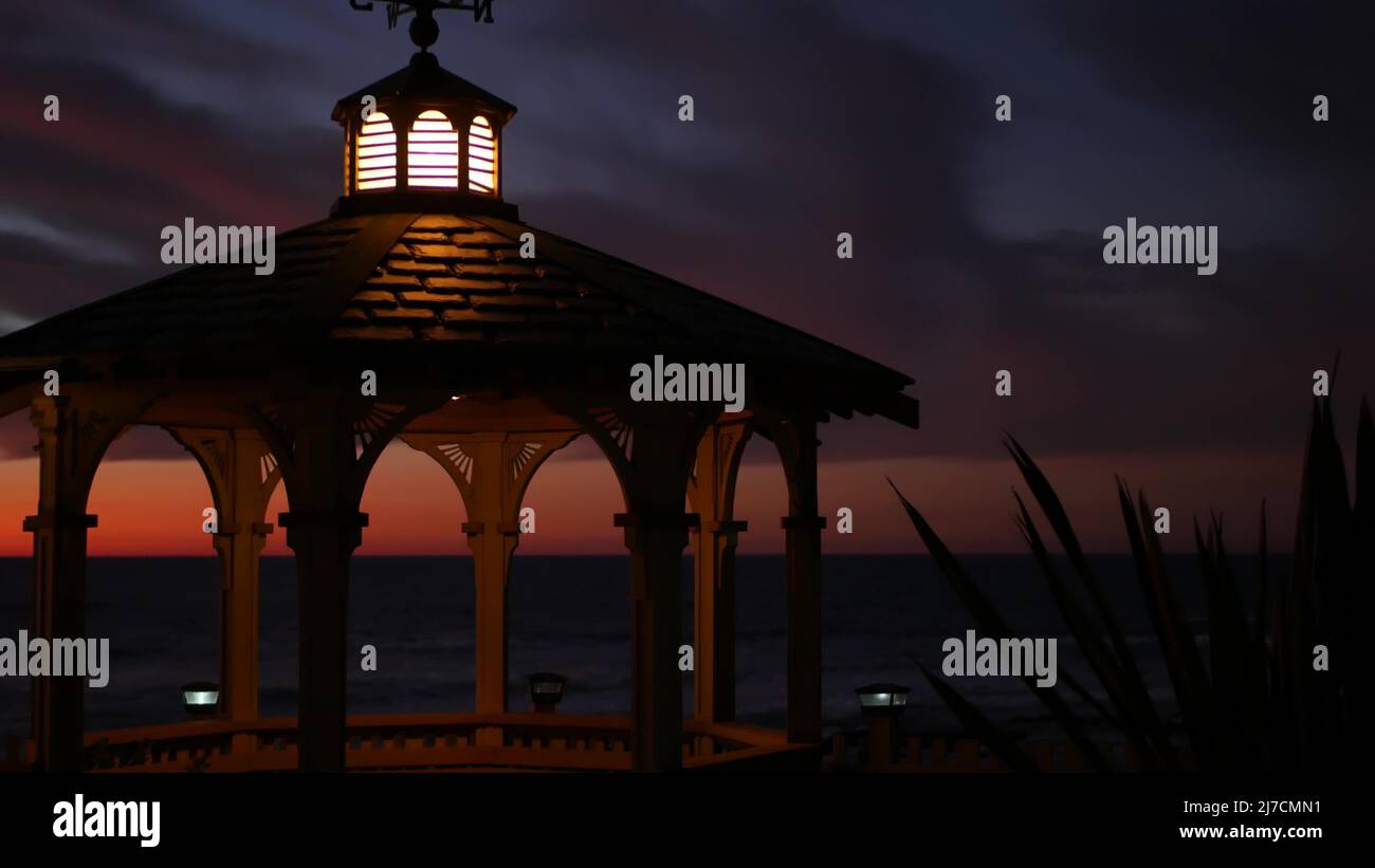 Sunset cloudscape and gazebo silhouette on beach, twilight dusk, clouds