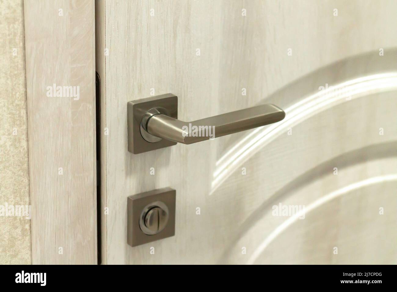 Metal door handle or doorknob with security lock on wooden background Stock Photo