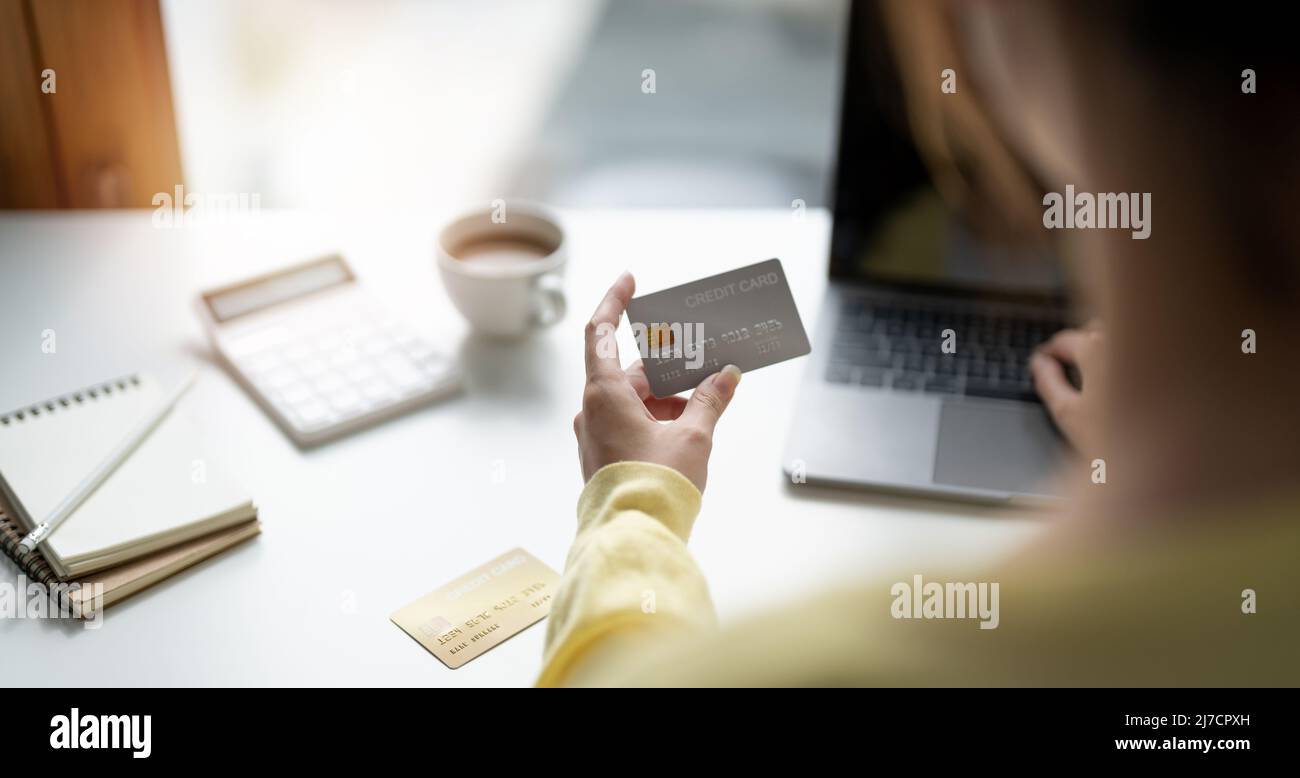 Close up of girl hold bank credit card and type on laptop, shopping online using computer, buying goods or ordering online, entering bank accounts and Stock Photo